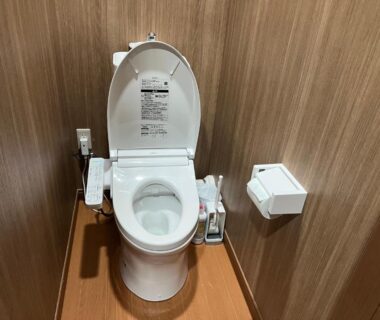 Compact bidet toilet with wood-paneled walls at Samurai Hotel Naraiso Nagano