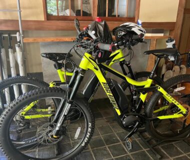 Mountain bikes with helmets stored near wooden entrance of ryokan in Nagano
