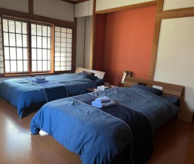 Two twin beds with blue linens, shoji screens and wooden floor at Samurai Hotel Naraiso, Nagano Japan