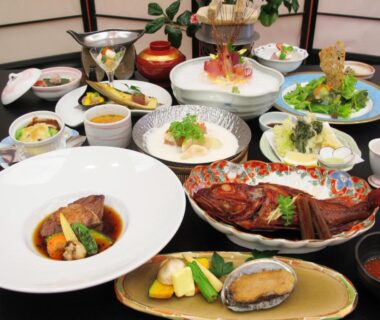 Assorted multi-course Japanese dishes with grilled fish, shellfish, tempura and small side dishes on lacquer table