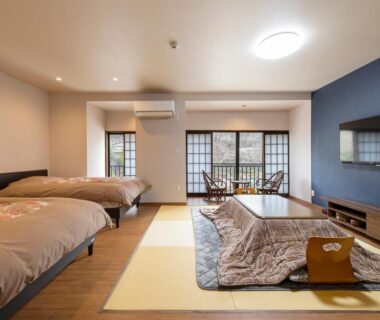 Spacious tatami-style room with low table, two western beds, shoji screens and window seating at Sanso Matsuya Ōita