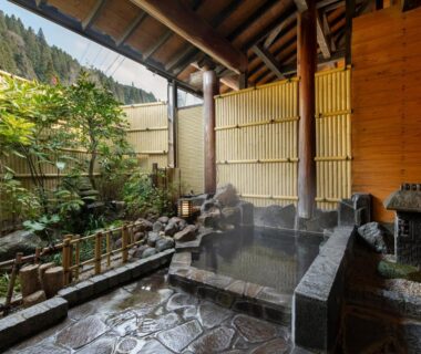 Stone onsen bathing area with bamboo fence and garden at Sanso Matsuya Oita
