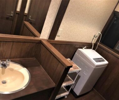 Sink and washing machine in a wooden ryokan utility area at Sanso Tanaka in Oita, Kyushu