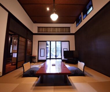 Tatami room with low wooden table, recessed seating, shoji screens and garden-view sliding doors at Sanso Tensui in Ōita