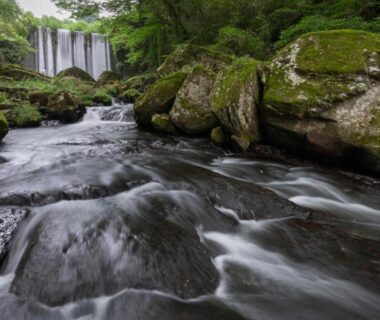 Flowing stream and cascading waterfall among mossy rocks at Sanso Tensui in Ōita, Kyūshū