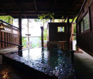 Covered wooden onsen bath with open side and garden view at Sanso Tensui, Ōita, Kyūshū