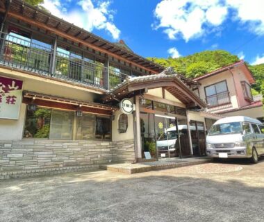 Traditional ryokan entrance with manicured trees and white service van at Sansou Nagisa, Kanagawa, Kantō