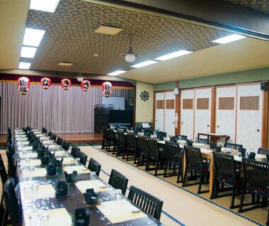 Tatami dining hall with rows of set tables, chairs and stage lanterns at Sansou Nagisa in Kanagawa, Kantō