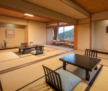 Spacious tatami guest room with low tables, zabuton cushions and hillside view at Sansuikan Kinryu in Shizuoka