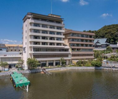 Multi-story ryokan on calm waterfront with dock and hillside buildings in Shizuoka, Chūbu, Japan