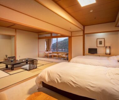 Tatami room with low table, two beds and balcony view at Sansuikan Kinryu in Shizuoka