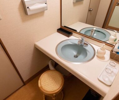 Compact washstand with round blue sink, mirror, toiletries and stool at Sansuikan Kinryu, Chūbu Shizuoka