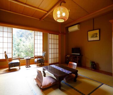 Sunlit tatami room with low table, shoji screens and window seating at Sansuisou in Kanagawa