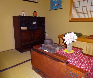 Tatami room with shoji window, wooden chest table, tea set and floral arrangement at Sansuisou, Kanagawa