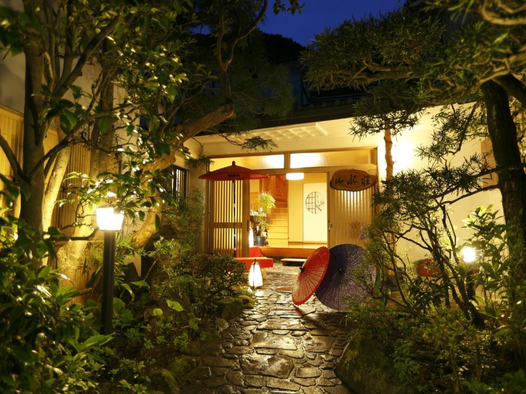 Lantern-lit entrance to Sansuisou Kanagawa Stone lantern-lit garden path leading to Sansuisou entrance with umbrellas and wooden doorway in Kanagawa