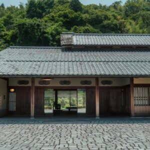 Cobblestone courtyard and wooden entrance of Sanyo-so with tiled roof and forested hillside in Shizuoka, Chūbu
