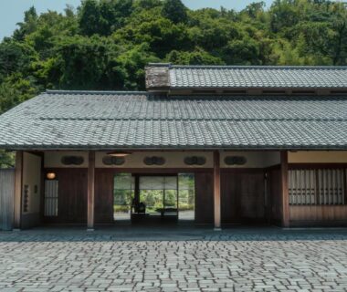 Cobblestone courtyard and wooden entrance of Sanyo-so with tiled roof and forested hillside in Shizuoka, Chūbu