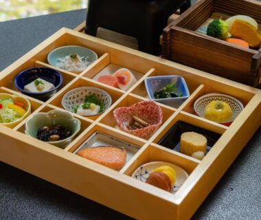 Wooden compartment box with assorted small Japanese dishes, grilled fish, pickles and simmered items at Sanyo-so Shizuoka