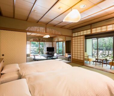 Traditional tatami room with bedding, shoji screens, garden view and seating at Sanyo-so, Shizuoka