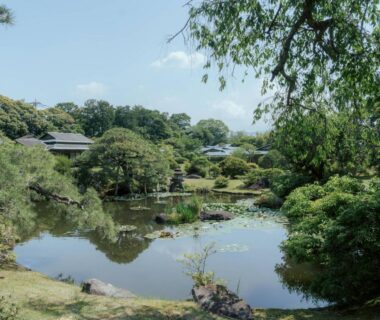 Tranquil Japanese garden pond with trees and traditional ryokan buildings at Sanyo-so in Shizuoka