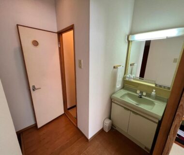 Small vanity sink with mirror beside hallway door at Marukoma Onsen Ryokan in Hokkaidō, Japan