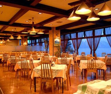 Warmly lit dining area with wooden tables and curtains at Marukoma Onsen Ryokan in Hokkaidō, Japan