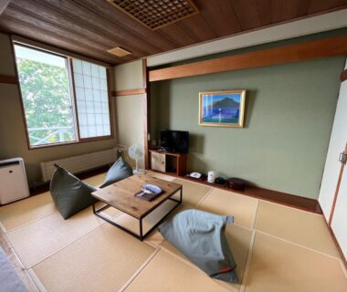 Tatami room with low table, floor cushions, shoji window and TV at Marukoma Onsen Ryokan in Hokkaidō