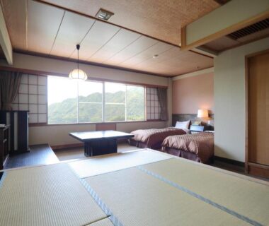 Spacious tatami room with two beds, low table and mountain view at Sarugakyo Hotel, Gunma, Kantō