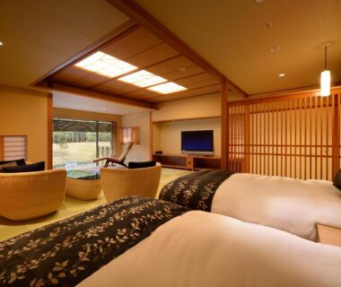 Spacious tatami room with twin beds, low seating area, shoji screens and garden view at Saryo Souen, Miyagi