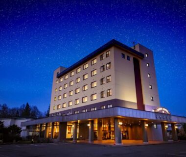 Illuminated Sasai Hotel exterior at night under a starry sky in Hokkaidō with lit entrance and parking area