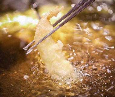 Chopsticks holding tempura frying in bubbling oil at Sasai Hotel in Hokkaidō