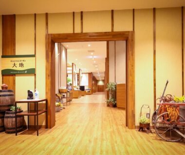 Warm wooden-floor lobby corridor with decorative barrels, seating and traditional decor at Sasai Hotel in Hokkaidō, Japan
