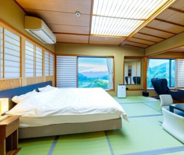 Spacious tatami room with Western bed, shoji screens, seating area and mountain views at Sasakura onsen Ryuunso Niigata