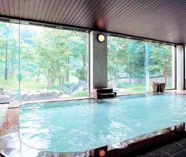 Indoor onsen bath with large windows overlooking a verdant garden at Sasakura onsen Ryuunso, Niigata