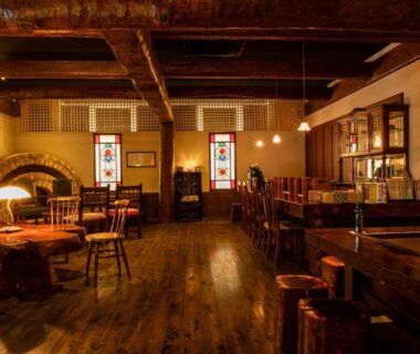 Interior lounge with exposed wooden beams, fireplace, stained glass windows and seating at Sasara in Gifu Chubu