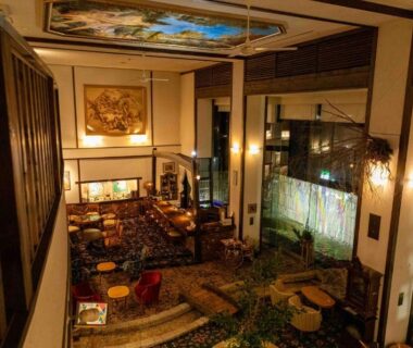 Warm ryokan lobby with seating, wooden beams, decorative ceiling painting and indoor garden at Sasara in Gifu