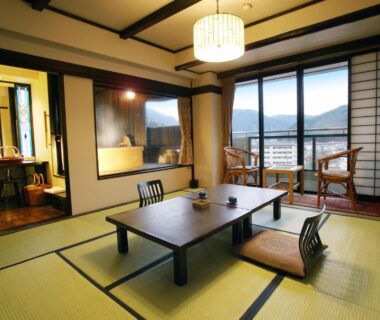 Tatami room with low table, shoji screens and balcony with mountain view at Sasara in Gifu