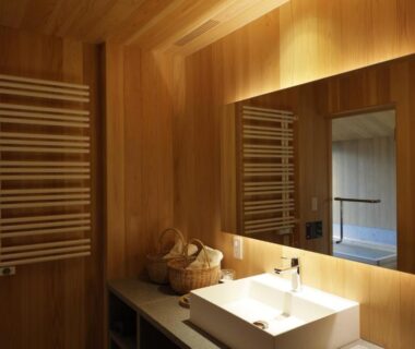 Wood-paneled bathroom with sink, mirror, towel radiator and basket at Satoyama Jujo in Niigata, Chūbu, Japan