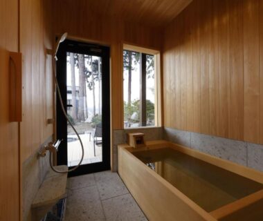 Wooden soaking tub and shower beside glass door at Satoyama Jujo The House Niigata Chūbu