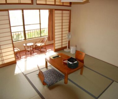 Bright tatami room with low table, zabuton cushions, shoji screens and small balcony seating at Sawatari Onsen Miyataya Ryokan, Gunma