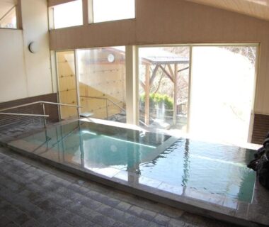 Indoor onsen bath with handrail and large windows at Sawatari Onsen Miyataya Ryokan, Gunma, Japan