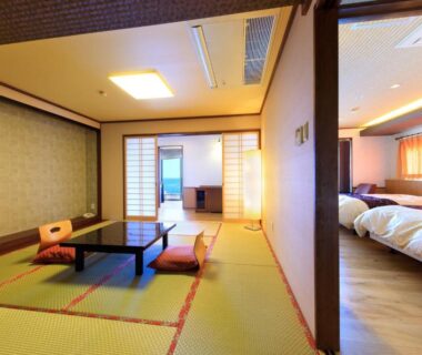 Tatami seating area with low table and shoji screens beside twin Western beds at Seaside Hotel Mimatsu Ooetei in Ōita