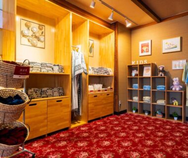 Guest yukata, slippers, and cubby shelving in warm-lit ryokan dressing area