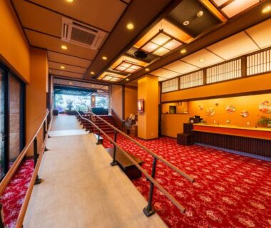 Warm ryokan lobby with red carpet, reception desk, shoji screens and entrance corridor at Seaside Hotel Mimatsu in Ōita