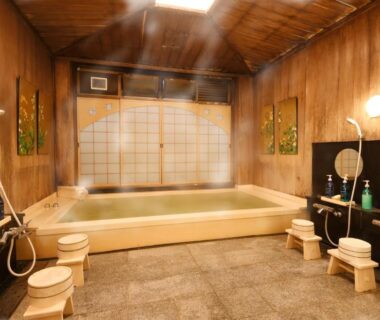 Wooden indoor onsen with soaking tub, washing stools and shoji screen at Seikoro Ryokan Kyoto