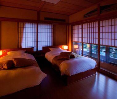 Room with twin beds, shoji screens and warm lighting at Seiryu-so in Shizuoka, Chūbu