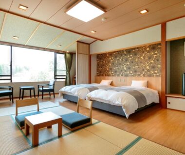 Spacious tatami room with twin beds, low table, shoji screens and garden view at Seiryukaku in Iwate