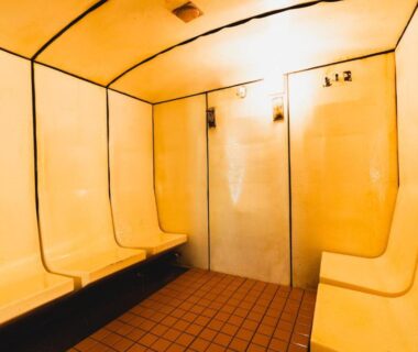 Yellow changing room with molded benches, tiled floor and locker doors at Seiryukaku in Iwate, Tōhoku