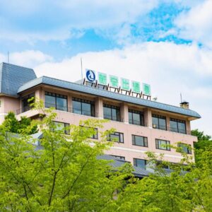 Multi story Seiryukaku building facade framed by green trees under blue sky in Iwate Tohoku