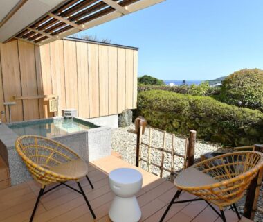 Wooden deck with outdoor stone bath, wicker chairs and garden view at Seizan Yamato, Shizuoka